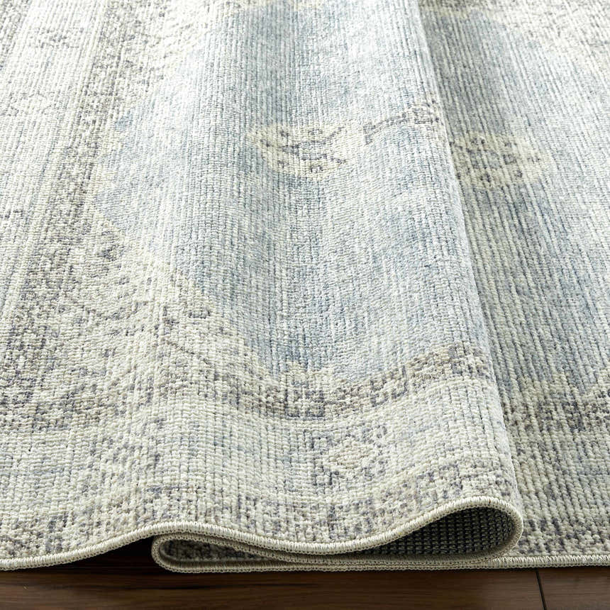 Close-up of the Lila Medallion Denim Area Rug featuring a traditional gray and denim medallion pattern and woven texture. Fold