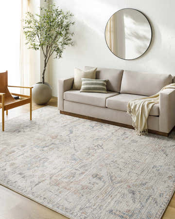 Living room with a Marlene Damask Off White & Blue Area Rug, beige sofa, olive tree, and round mirror. Roomscene-Rectangle