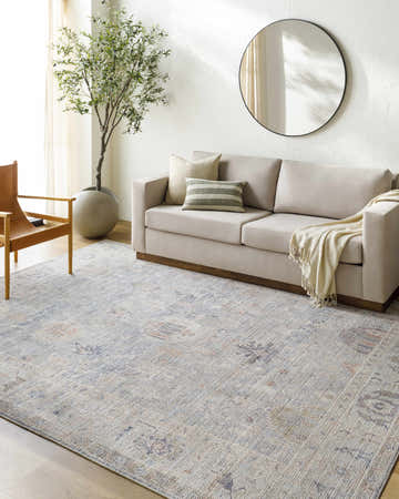 Living room scene with Marlene Damask Cream & Blue Area Rug, beige sofa, leather chair, and potted tree. Farmhouse style. Roomscene-Rectangle