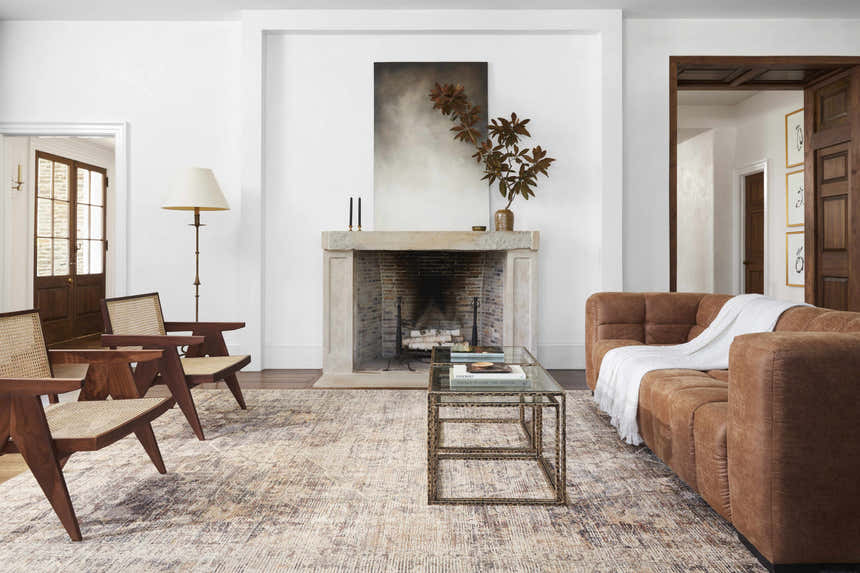 Living room scene with a Marlene Medallion Brown Area Rug, brown sofa, fireplace, and mid-century modern chairs. Styleshot