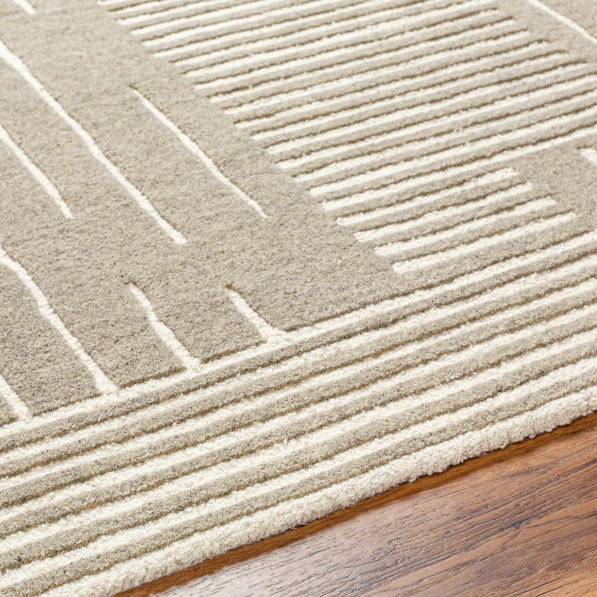 Close-up of the hand-tufted Akuji Area Rug. Features a contemporary geometric design in light peach and medium gray wool. Texture