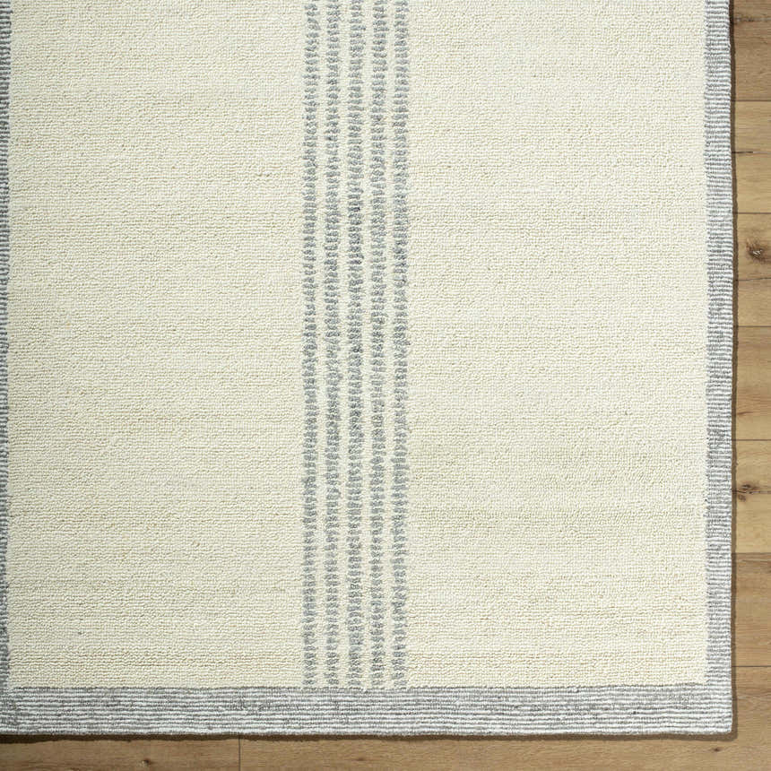 Close-up of the hand-tufted Ande Cream Area Rug. Features a cream base with gray striped border and accents. 100% Wool. Corner