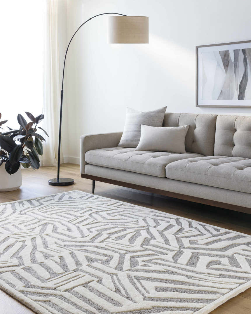 Living room scene with a gray sofa and Avian Gray Wool Area Rug featuring a cream and taupe geometric pattern. Roomscene-Rectangle