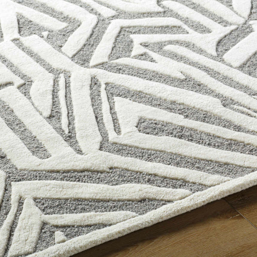 Close-up of the Avian Gray Wool Area Rug showing cream geometric patterns on a taupe background. Hand-tufted texture. Texture