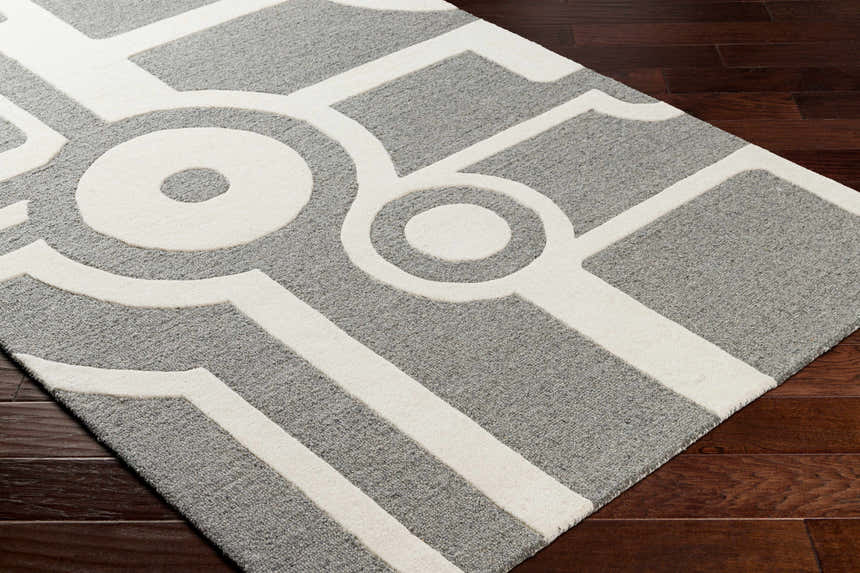 Close-up of the contemporary Daryl Area Rug. Gray wool rug with a geometric white circle and line pattern. Corner
