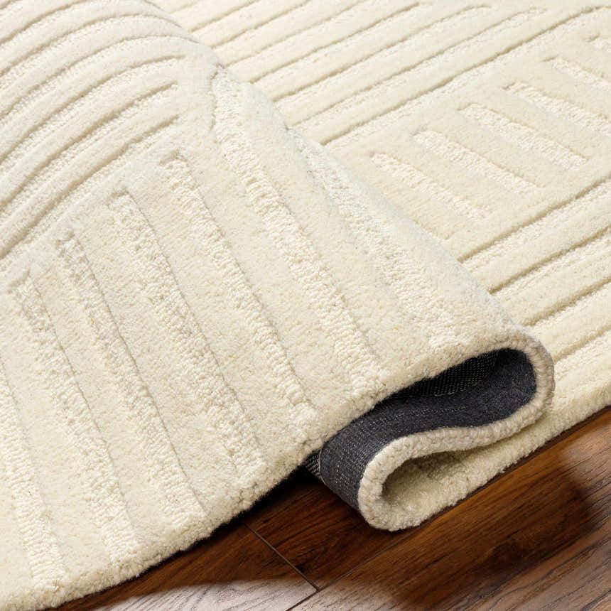 Close-up of the textured, off white Whan Area Rug showing its hand-tufted wool construction and subtle striped pattern. Fold