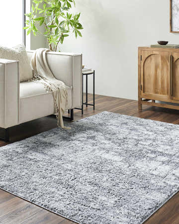 Living room scene with a light silver Suubi Area Rug, neutral sofa, wood cabinet, and dark wood floors. Roomscene-Rectangle