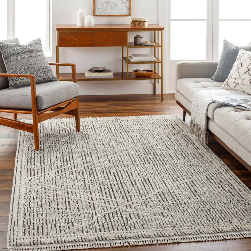 Living room scene with gray sofa and chair featuring the Luuk Area Rug in dark brown and ivory. Roomscene-Rectangle