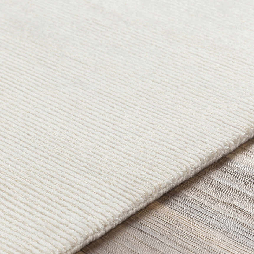 Close-up of the hand-knotted Sabinsville Carpet. The rug is a creamy white color with a subtle ribbed texture. Texture