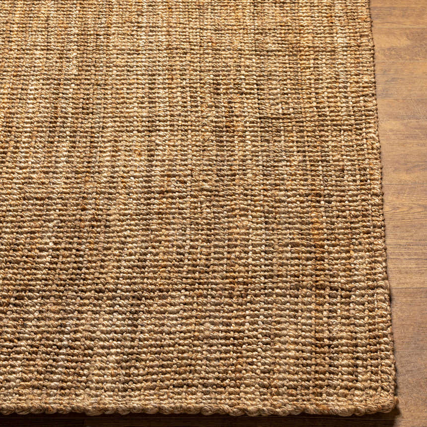 Close-up of the hand woven Ambel Chocolate Brown Camel Jute Area Rug showing texture and detail on wood floor. Front