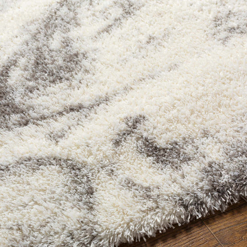 Close-up of the Delma Area Rug. Shag texture with cloud gray, dark gray, and off-white hues. Soft polyester rug. Texture