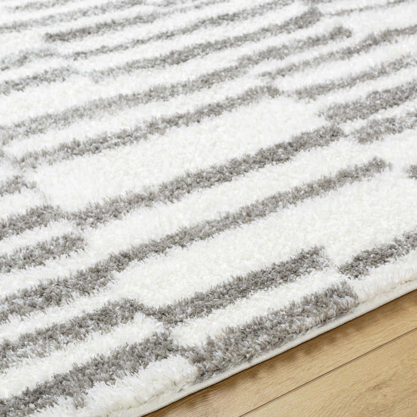 Close-up of the Kuron Area Rug showing its charcoal and off-white shag stripes and soft texture. Texture
