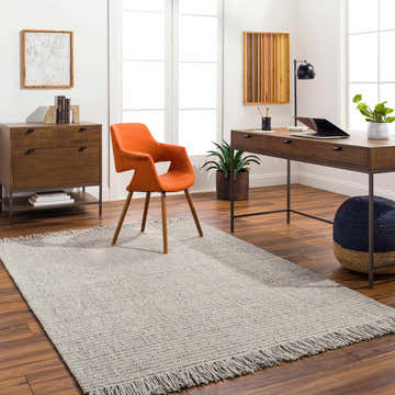 Home office with a Desma Taupe Area Rug, wood desk, orange chair, and natural light from a large window. Roomscene-Rectangle