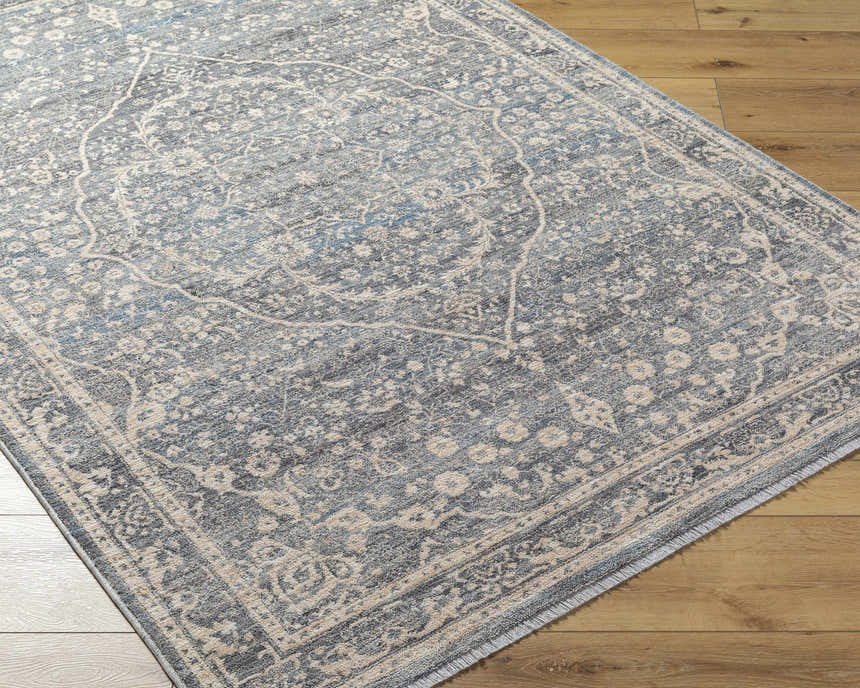 Close-up of the Anouk Area Rug showcasing its traditional dark gray, blue, and beige floral pattern on wood floors. Corner