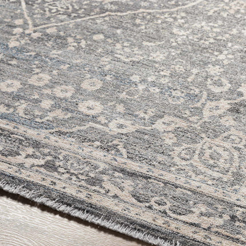 Close-up of the gray Anouk Area Rug showing its traditional pattern and soft texture. Clearance rug on wood floor. Texture