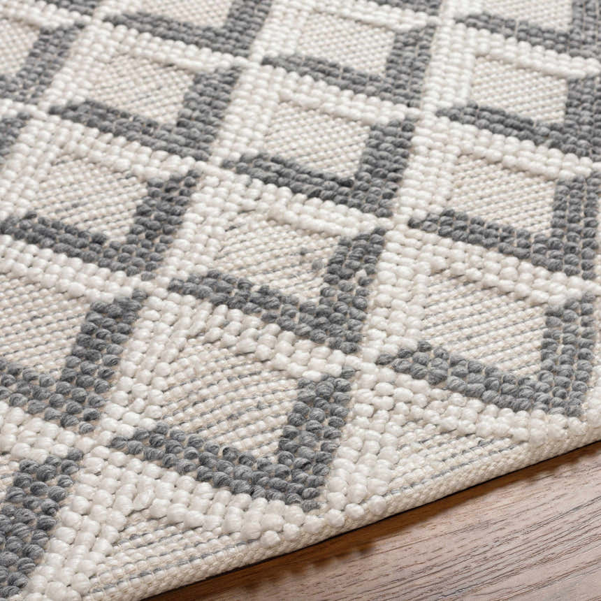 Close-up of the Maik Area Rug, showing gray and light gray geometric pattern and hand-woven texture. Texture