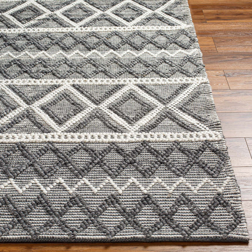 Close-up of the hand woven Yuka Area Rug. Dark gray and natural gray geometric pattern on a textured, recycled PET yarn rug. Front