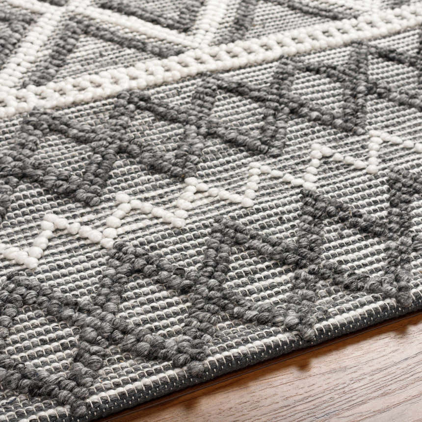 Close-up of the hand woven Yuka Area Rug. Dark gray and natural gray geometric pattern with raised texture. Texture