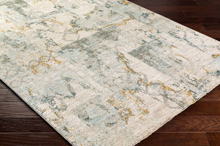 Close up of the Adlai Textured Rug with Fringes in off white, blue, mustard, and gray on dark wood floors. Corner