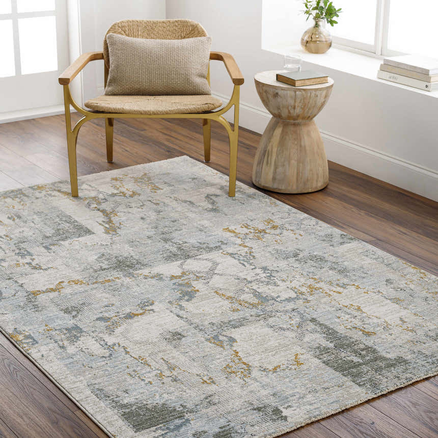 Living room scene with a textured Adlai Rug in dusty sage, ink blue, and mustard colors. Woven chair and wood side table. Roomscene-Rectangle