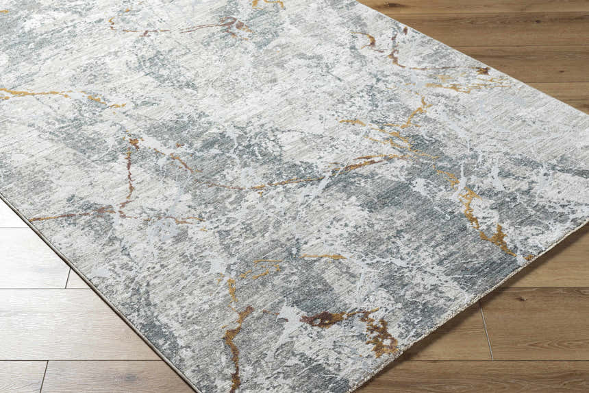 Close-up of the Asena Textured Rug. Abstract pattern in caramel, copper, gray, and brown on a textured polyester rug. Corner