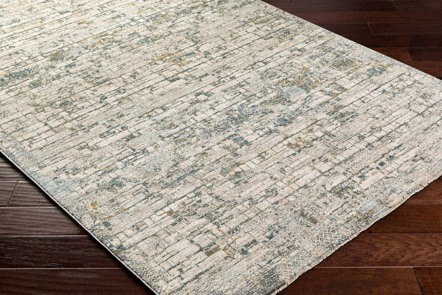 Close-up of the Chaka Textured Rug. Features a contemporary design in off-white, teal, and mustard on a dark wood floor. Corner