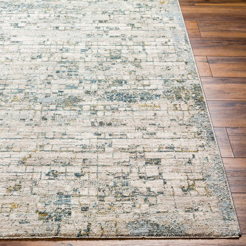 Close-up of the Chaka Textured Rug. Off-white rug with a distressed geometric pattern in teal, mustard, and gray on wood floors. Front