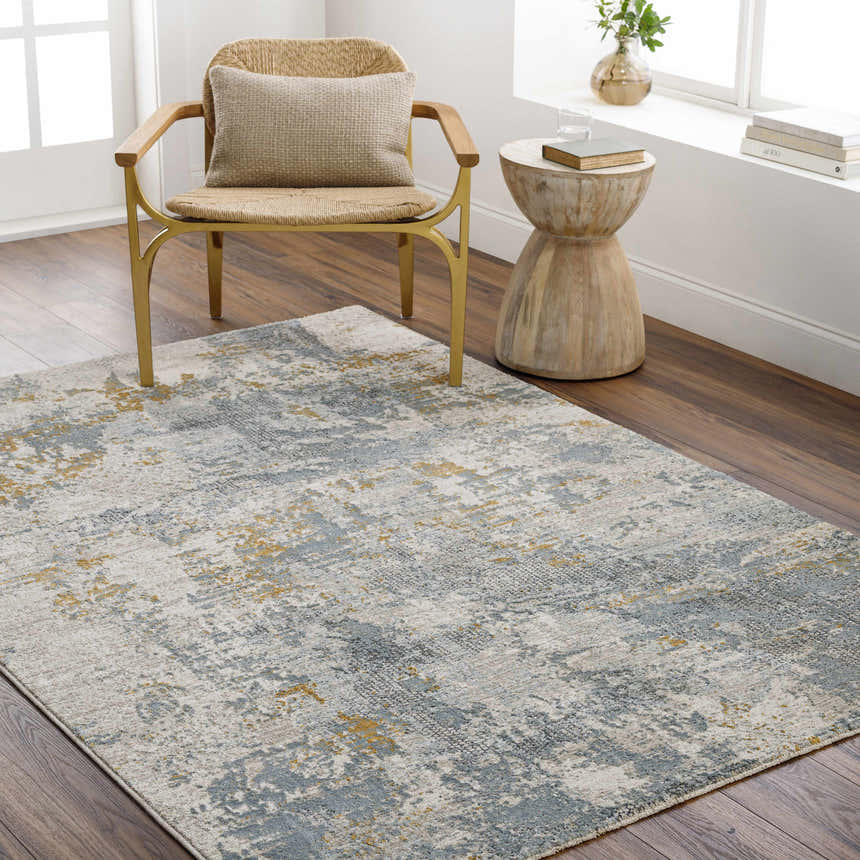 Living room scene with a Chaya Textured Abstract Rug in dusty sage, ink blue, and mustard under a chair and side table. Roomscene-Rectangle