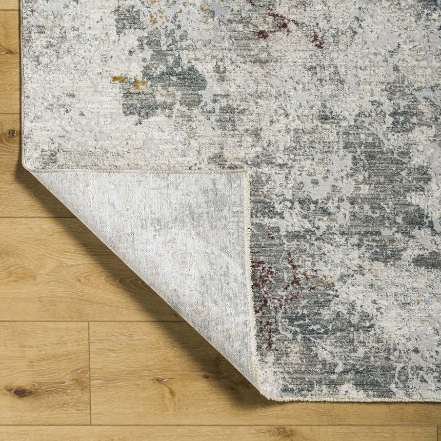 Close-up of the Edana Textured Rug showing its gray, brown, and cream abstract pattern and soft texture. Fold