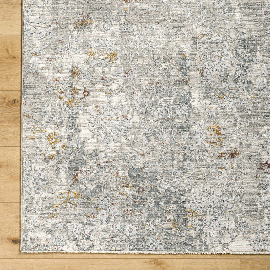 Close-up of the Ifama Textured Rug. Abstract pattern in light gray, medium gray, and light brown on a wood floor. Corner