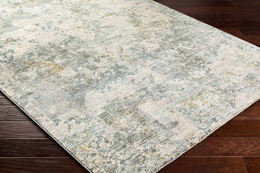 Close-up of the Pizi Textured Rug. Features a contemporary design with dusty sage, blue, and mustard hues. Corner