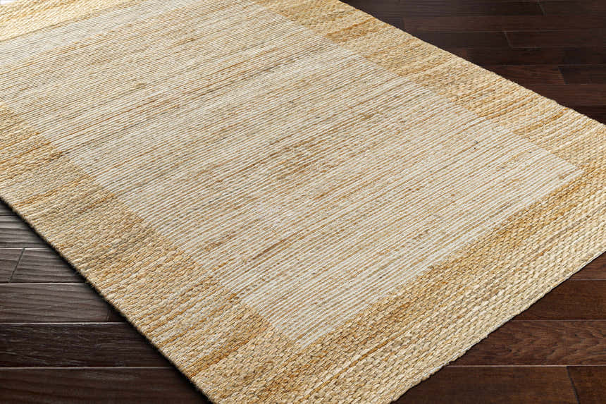 Close-up of the hand-woven Jojen Jute Area Rug in lambswool and light brown on dark wood flooring. Farmhouse style. Corner