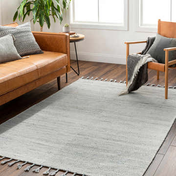 Living room scene with a beige leather sofa, wood chair, and Anaya Beige & Blue Area Rug with tassels on dark wood floors. Roomscene-Rectangle
