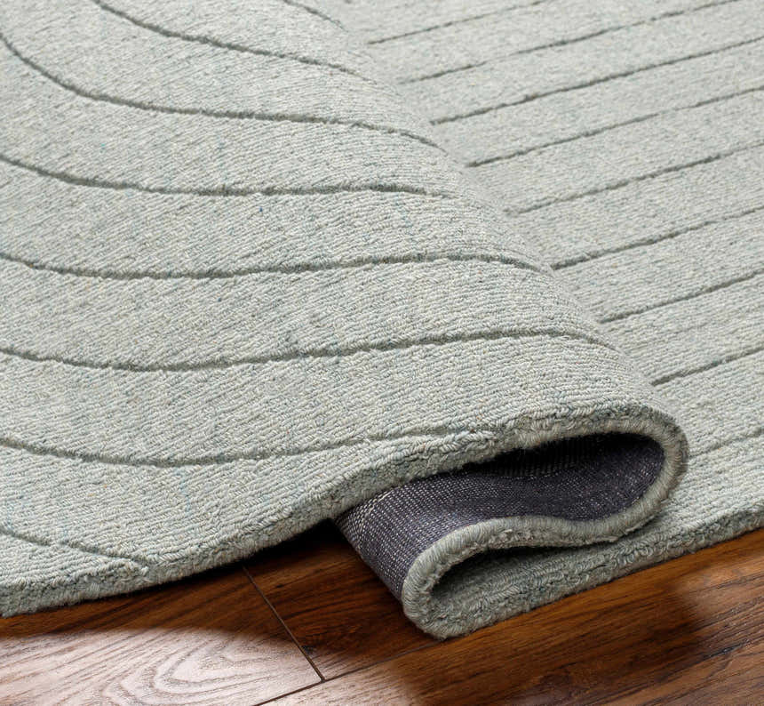 Close-up of the hand-loomed Ayumi Area Rug. The wool rug has a subtle gray striped pattern and a soft, inviting texture. Fold