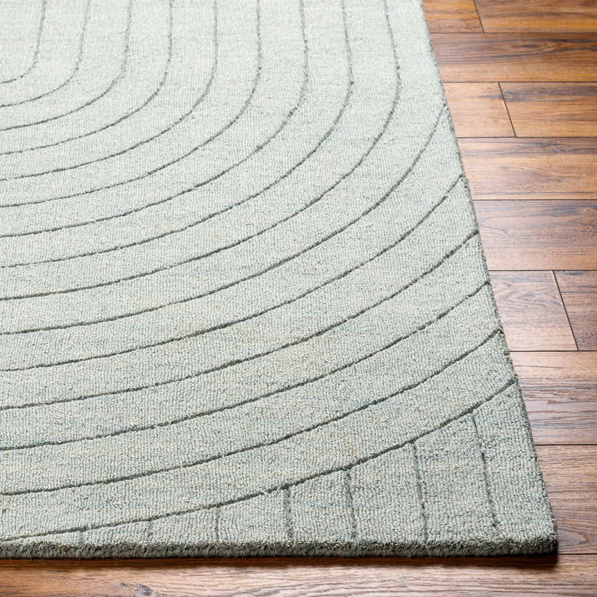 Close-up of the hand-loomed Ayumi Area Rug in silver gray wool. Contemporary design with curved lines on wood floor. Front
