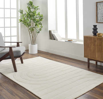Living room scene with a beige Neci Area Rug, gray chair, wood cabinet, and large window. Roomscene-Rectangle