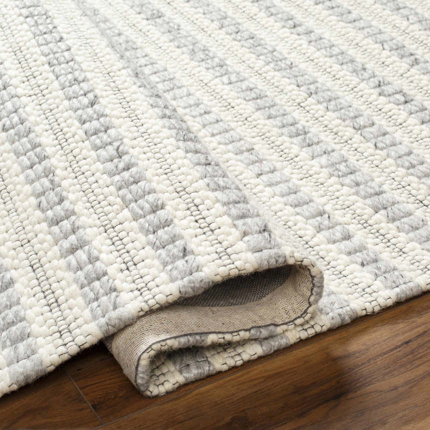 Close-up of the hand-woven Laleh Gray Area Rug showing its beige and rose cream geometric pattern and wool texture. Fold