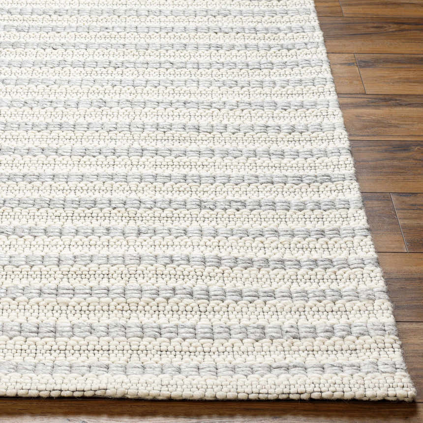 Close-up of Laleh Gray Area Rug showing hand-woven texture, beige and rose cream colors, on wood floor. Front