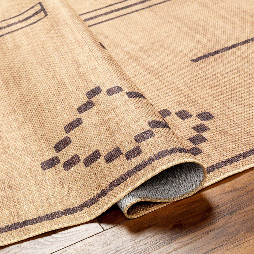Close-up of the Fathi Washable Area Rug. Camel and dark brown geometric pattern on a woven, recycled fabric texture. Fold