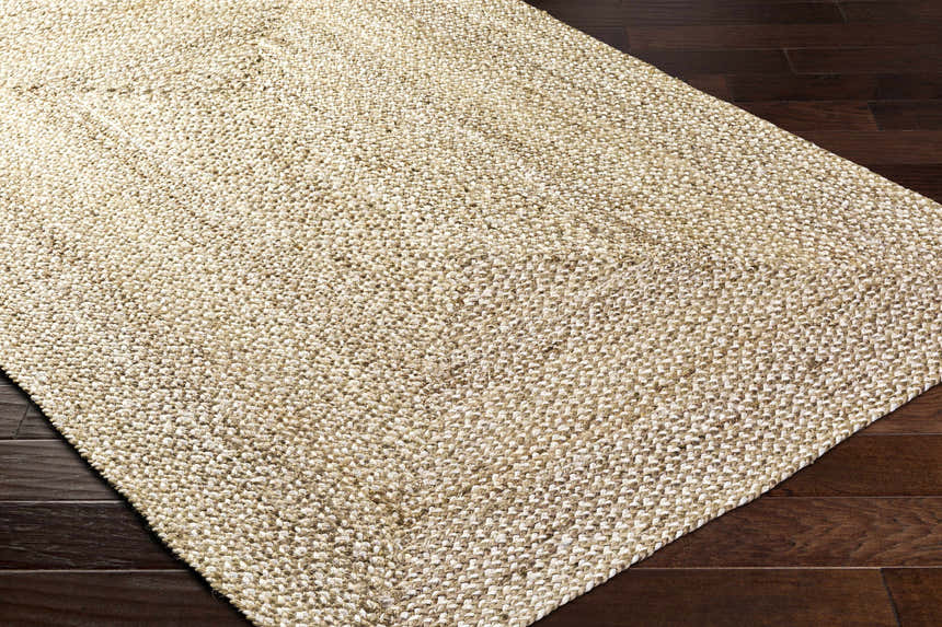 Close-up of the hand-loomed Elkie Area Rug in lambswool and light brown jute, showing texture and weave detail on dark wood floor. Corner