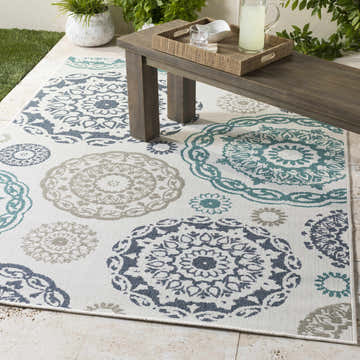 Outdoor patio scene with Shonkin Area Rug in navy, taupe, and teal under a wooden bench with drinks. Roomscene-Rectangle