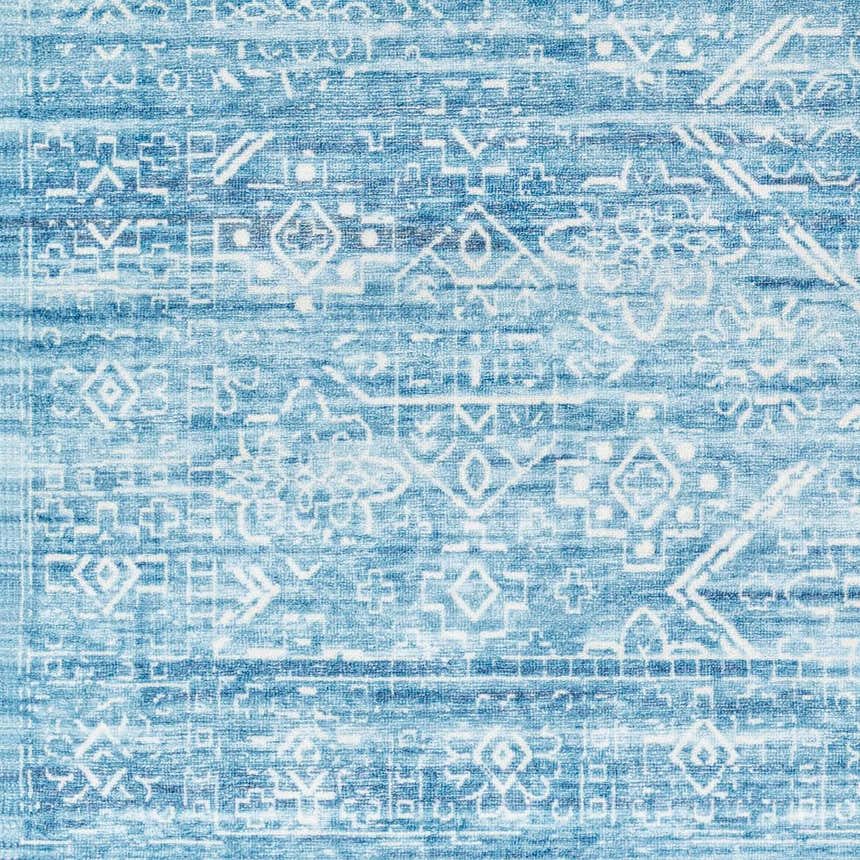 Close-up of Blake Arctic Sky Washable Area Rug. Features a geometric pattern in shades of blue, denim, and white. Swatch