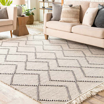 Living room scene with a cream sofa and the Siguinon Area Rug, a hand-woven wool rug with a geometric black and cream pattern. Roomscene-Rectangle