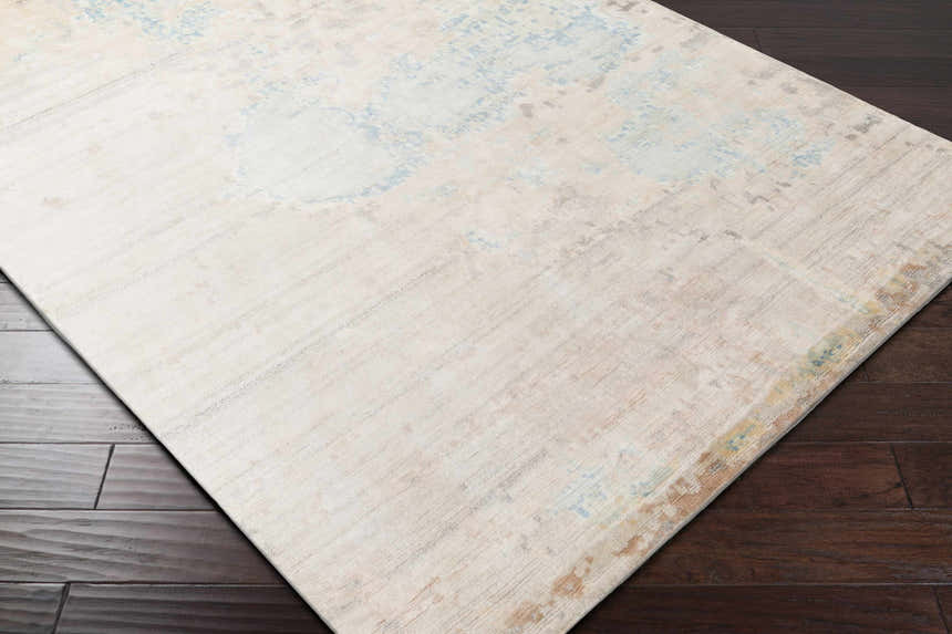 Close-up of the Simon Area Rug showing its cream, light blue, and tan contemporary design and hand-knotted texture. Corner