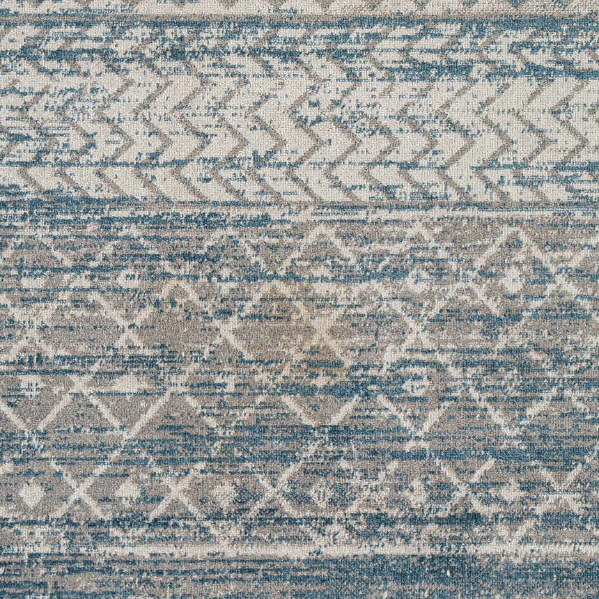 Close-up of the Tambac Blue Washable Area Rug showing a geometric pattern in blue, gray, and light gray hues. Swatch