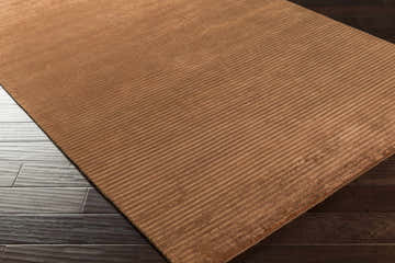 Close-up of the Sjafb Area Carpet, a hand-knotted runner with a linear pattern in warm brown tones on dark wood floors. Corner