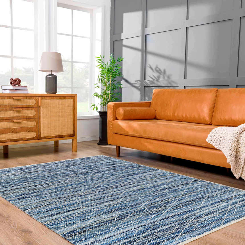 Living room scene with a Gurit Blue Area Rug, tan leather sofa, wood cabinet, and gray accent wall. Roomscene-Rectangle