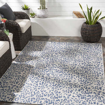 Outdoor patio scene with wicker chairs and a blue leopard print Skipsea Blue Leopard Performance Rug. Roomscene-Rectangle