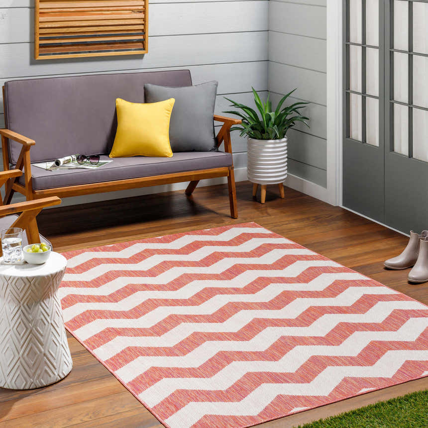 Outdoor patio scene with a coral and white chevron Cheri Lambswool Area Carpet, gray sofa, and potted plant. Roomscene-Rectangle