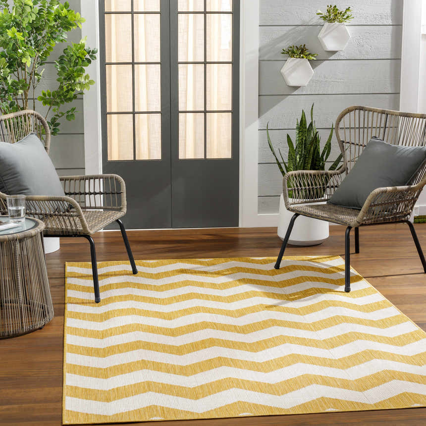 Outdoor patio scene with a Cheri Bone Area Carpet, wicker chairs, gray pillows, and wood floors. Roomscene-Rectangle